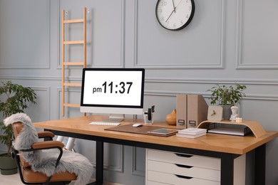 Photo of Stylish workplace with computer, houseplants and stationery on wooden desk near grey wall at home