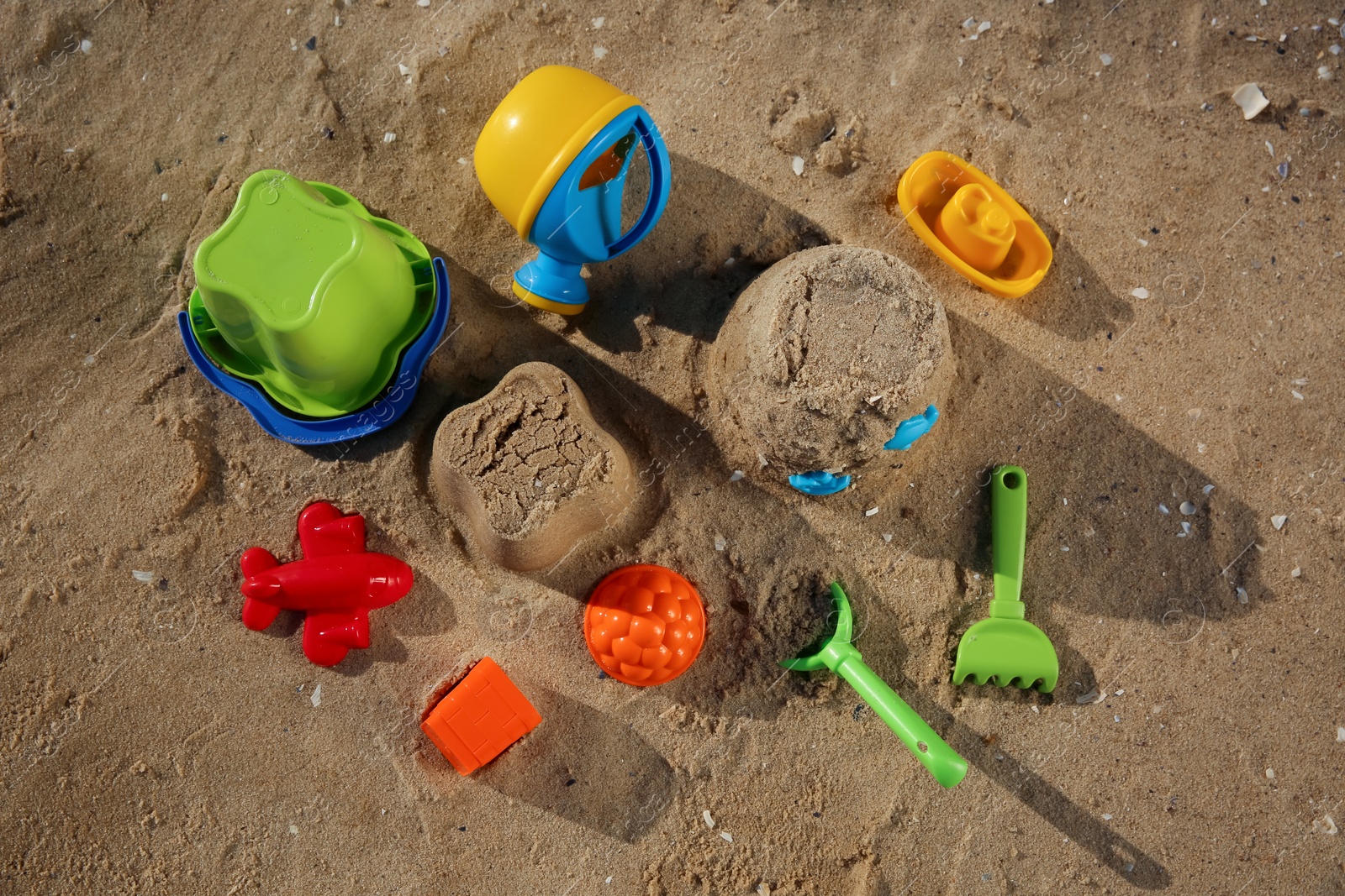 Photo of Set of plastic beach toys on sand, flat lay. Outdoor play