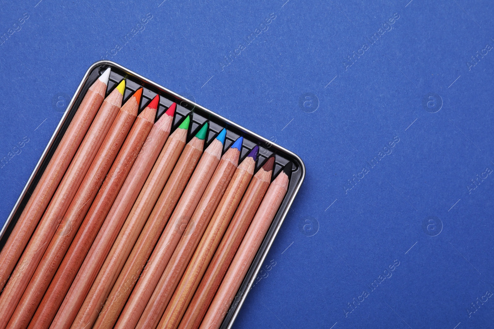 Photo of Colorful pastel pencils in box on blue background, top view with space for text. Drawing supplies
