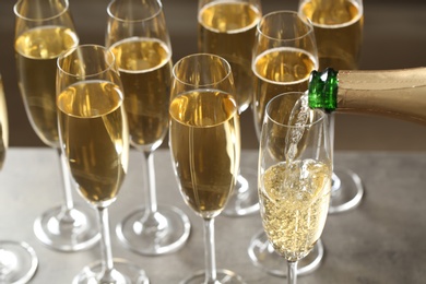 Pouring champagne into glasses on table, closeup view