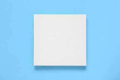 Photo of Blank canvas on light blue background, top view. Space for design