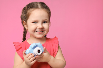 Little photographer with toy camera on pink background