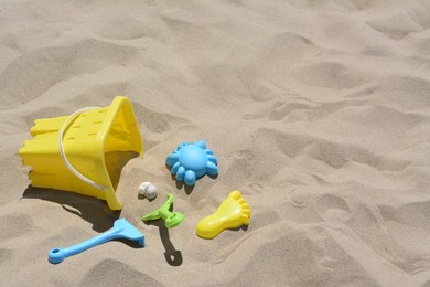Photo of Bright plastic bucket, rake and shovel on sand. Beach toys. Space for text