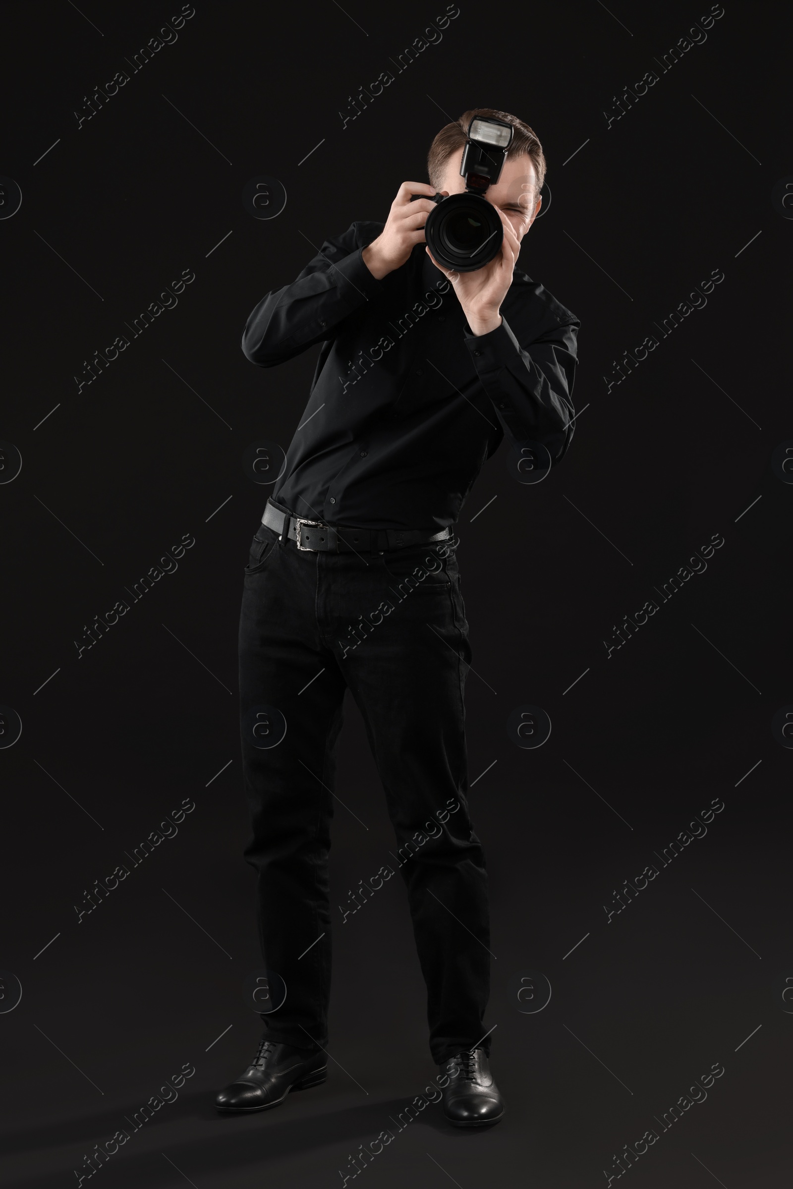 Photo of Professional photographer taking picture on black background