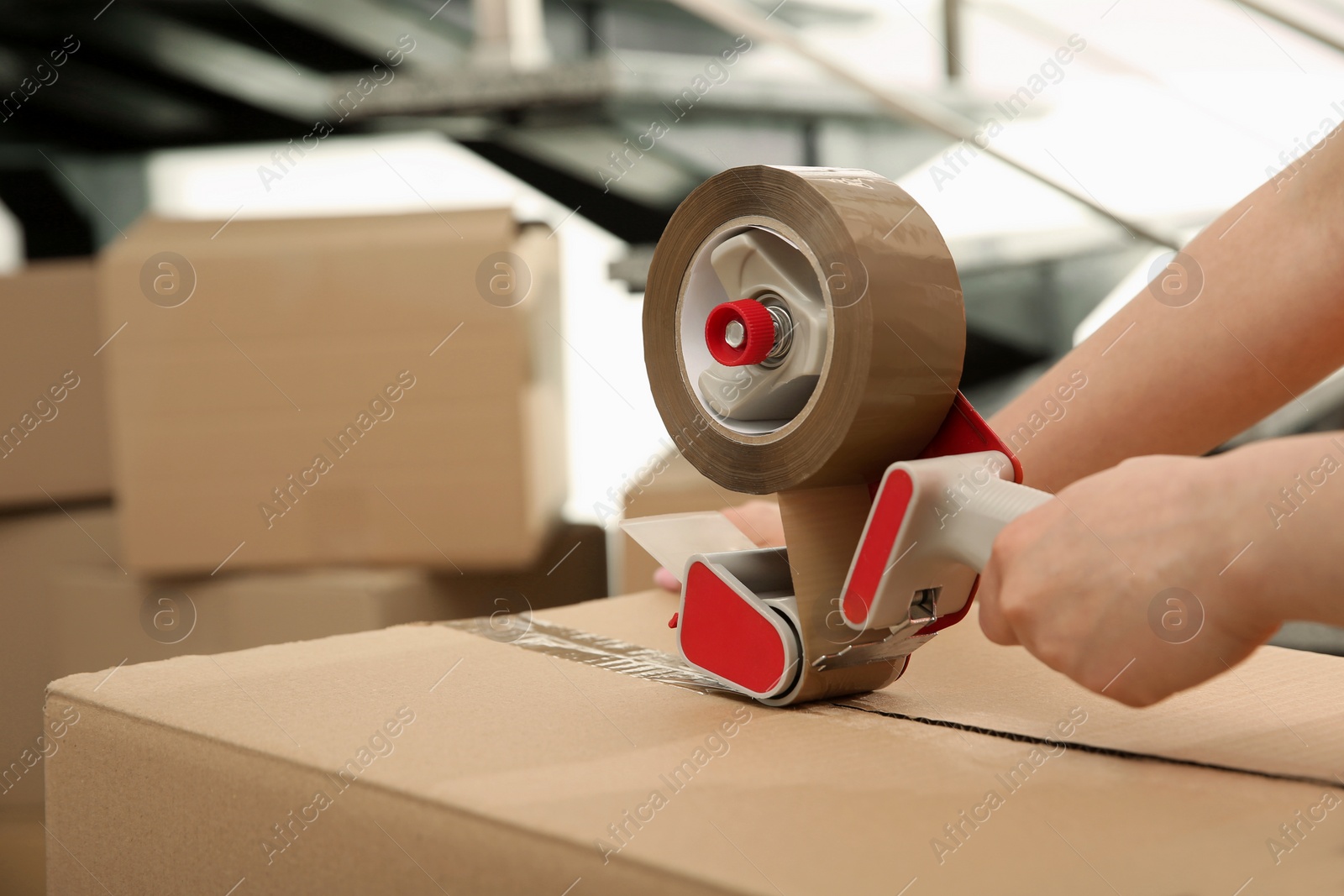 Photo of Worker taping cardboard box indoors, closeup. Space for text