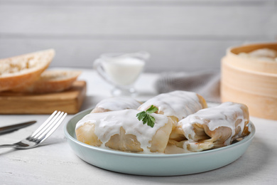 Photo of Delicious cabbage rolls served on white wooden table. Space for text