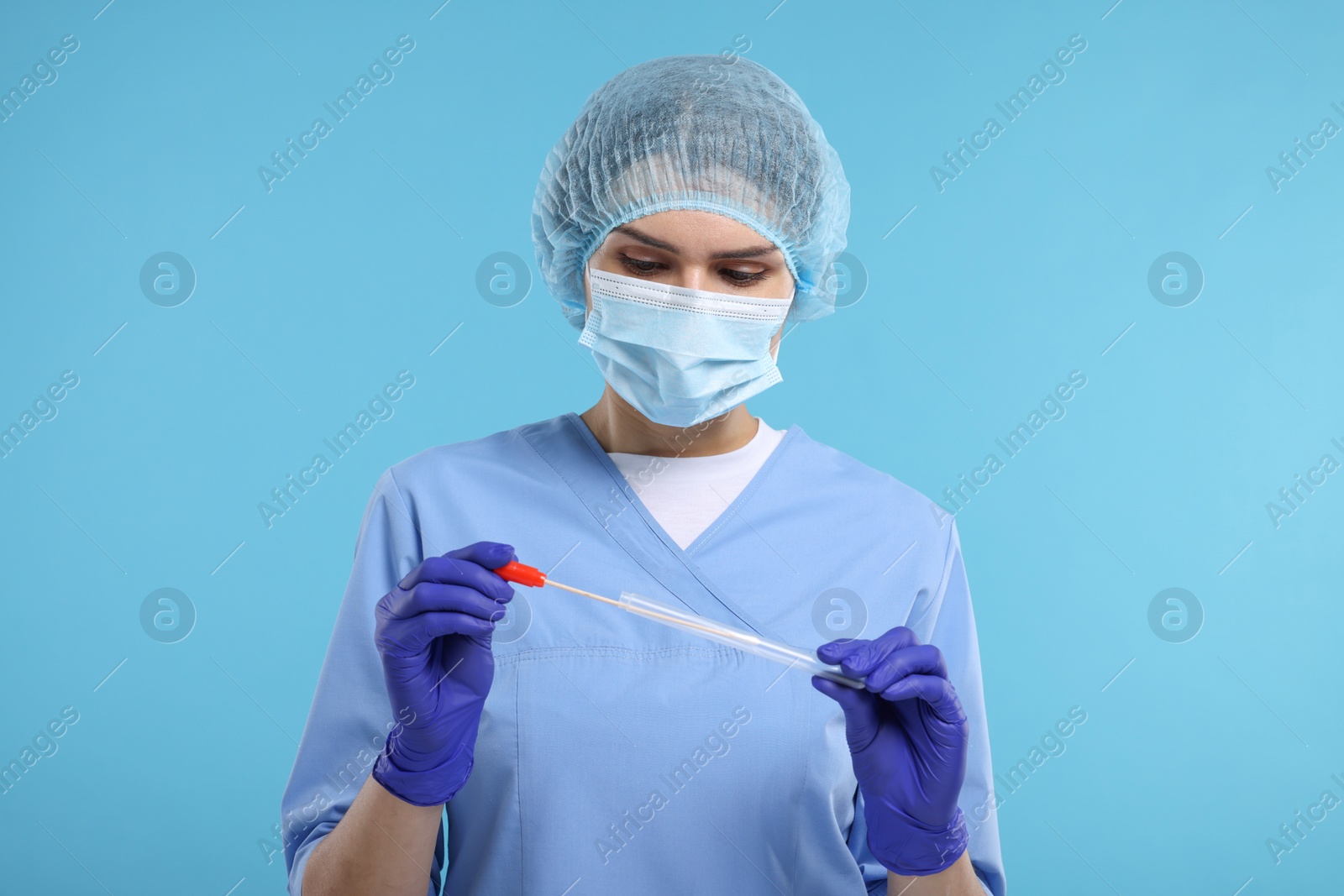 Photo of Laboratory testing. Doctor with cotton swab and tube on light blue background