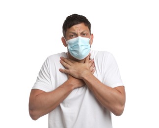 Man in medical mask suffering from pain during breathing on white background