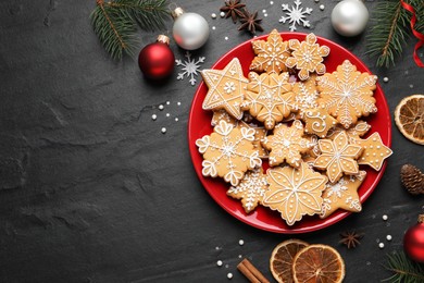 Photo of Tasty Christmas cookies and festive decor on black table, flat lay. Space for text