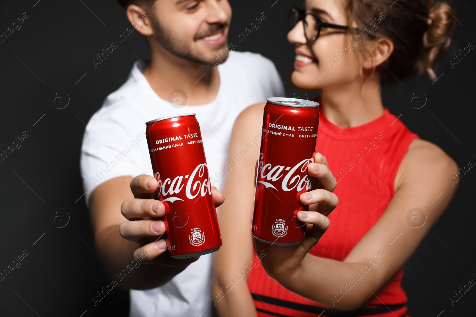 Photo of MYKOLAIV, UKRAINE - NOVEMBER 28, 2018: Young couple with Coca-Cola cans on dark background