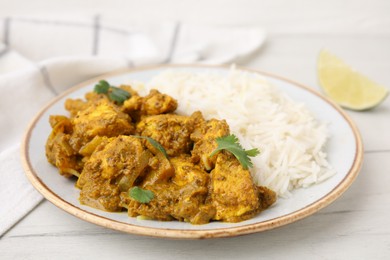 Photo of Delicious chicken curry with rice on white wooden table