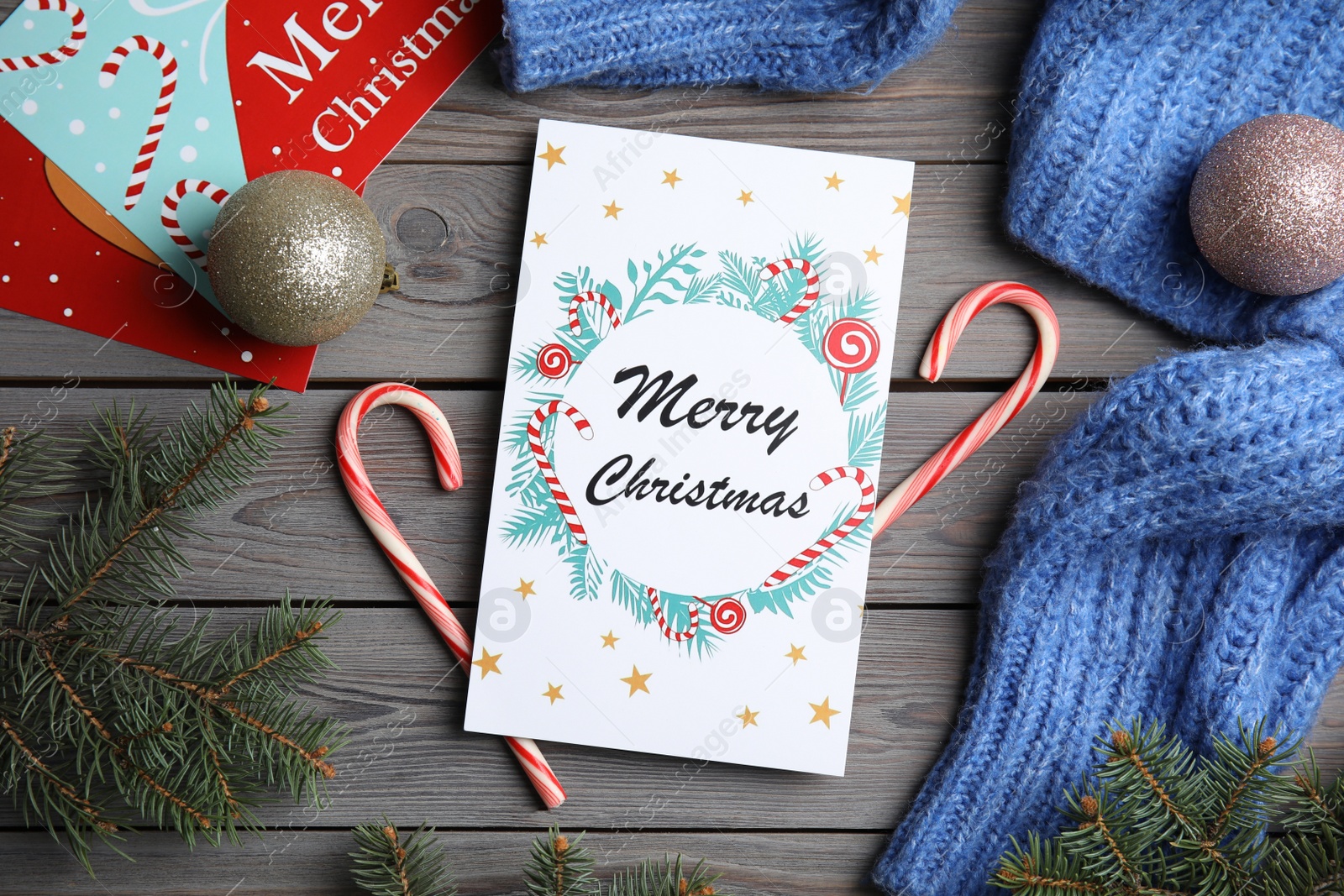 Photo of Flat lay composition with Christmas card and festive decor on grey wooden background