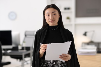 Photo of Portrait of beautiful businesswoman with documents in office