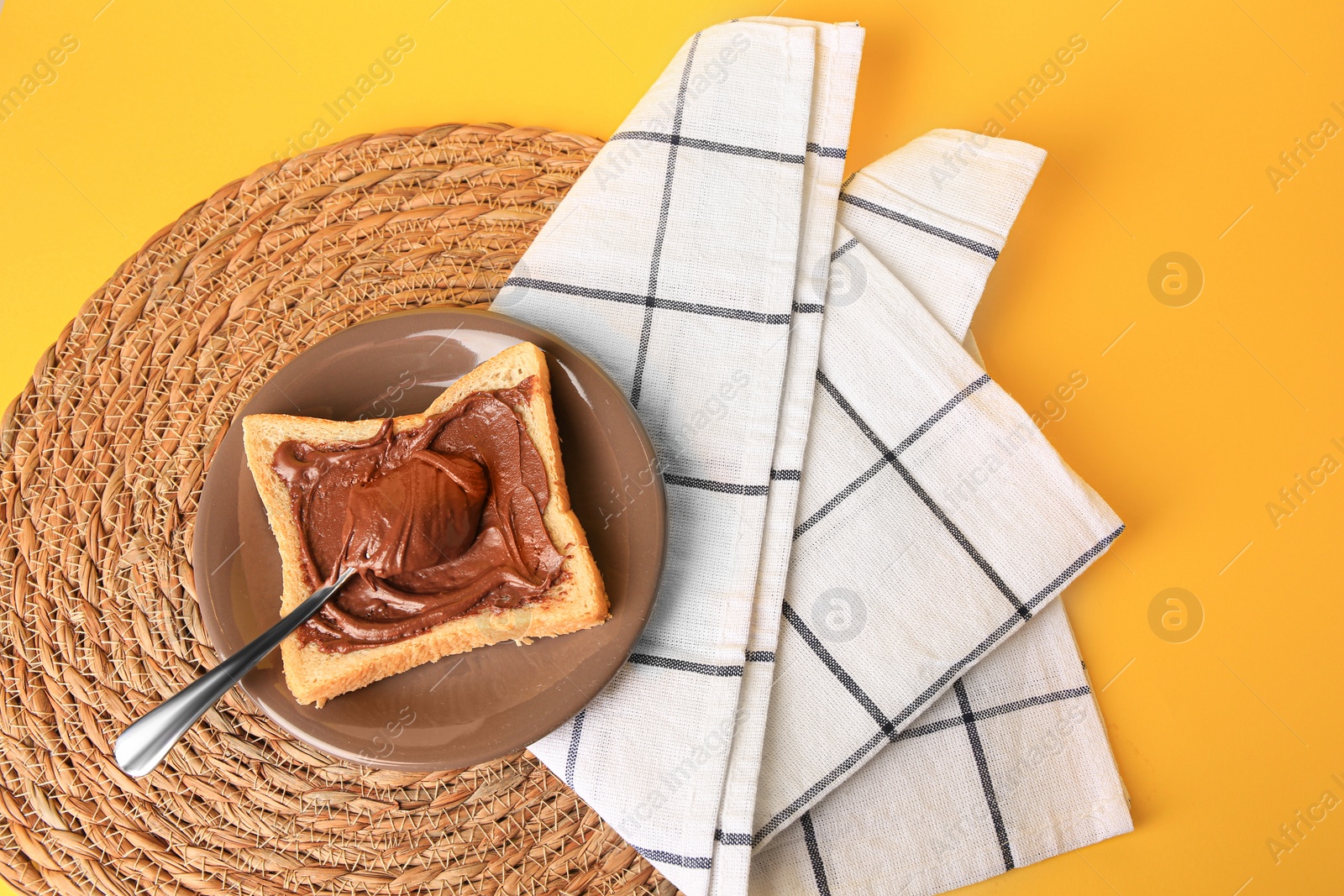 Photo of Tasty toast with chocolate paste on yellow background, top view. Space for text