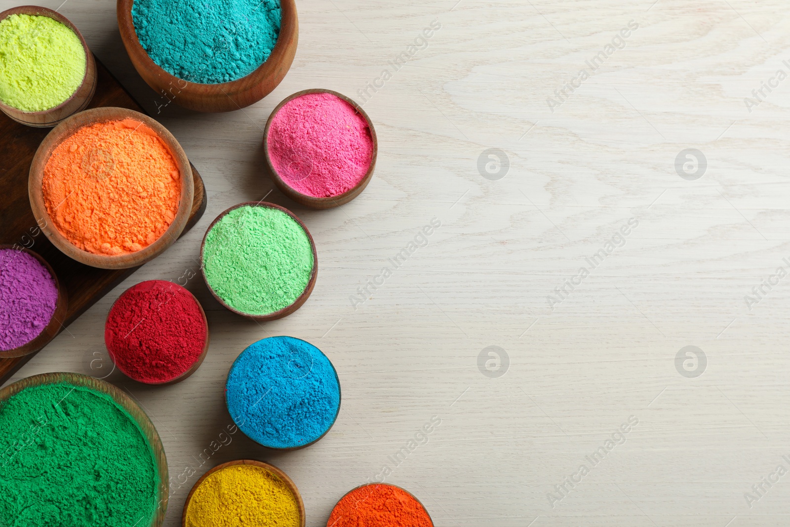 Photo of Colorful powder dyes on white wooden background, flat lay with space for text. Holi festival