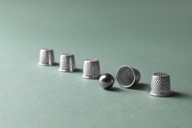 Metal thimbles and ball on pale olive background. Thimblerig game