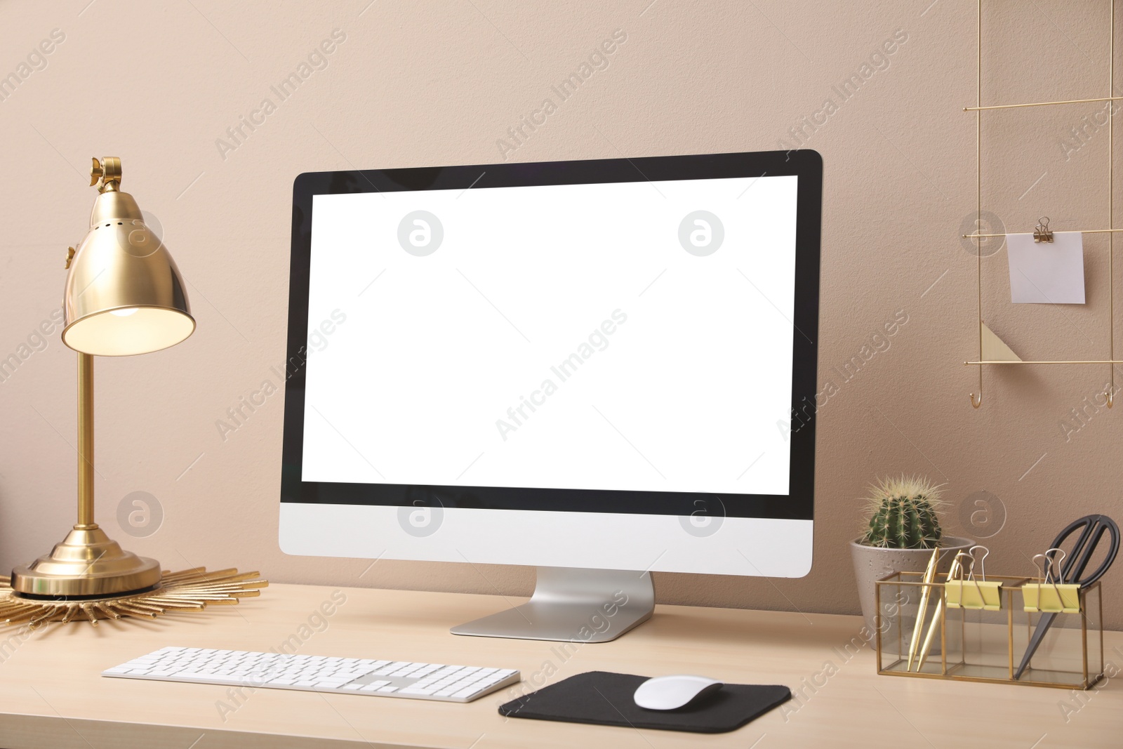 Photo of Stylish workplace with modern computer near beige wall indoors. Space for text