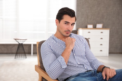 Portrait on handsome young man sitting in chair indoors