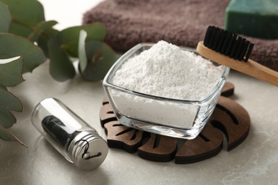 Photo of Tooth powder, brush and floss on light grey table, closeup