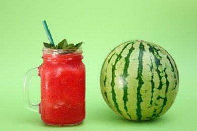 Photo of Glass of delicious drink and fresh watermelon on light green background