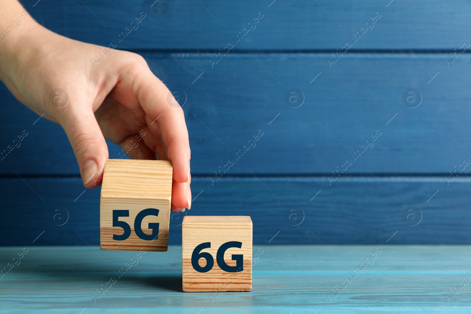 Photo of 6G and 5G technology, Internet concept. Woman with wooden cubes at turquoise table, closeup. Space for text