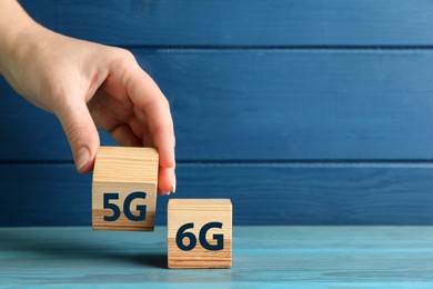 Photo of 6G and 5G technology, Internet concept. Woman with wooden cubes at turquoise table, closeup. Space for text