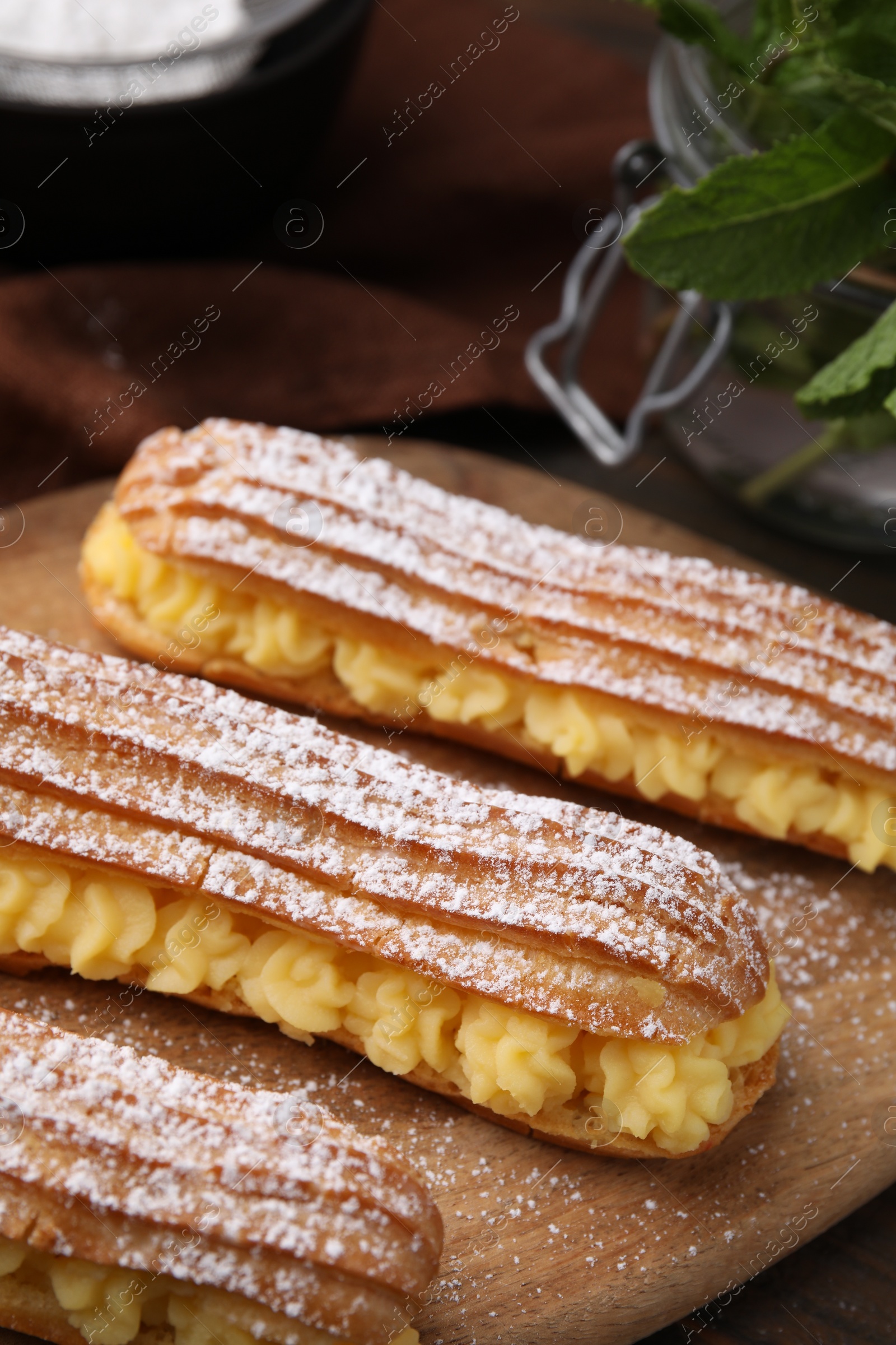 Photo of Delicious eclairs filled with cream on table