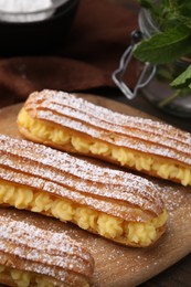 Photo of Delicious eclairs filled with cream on table