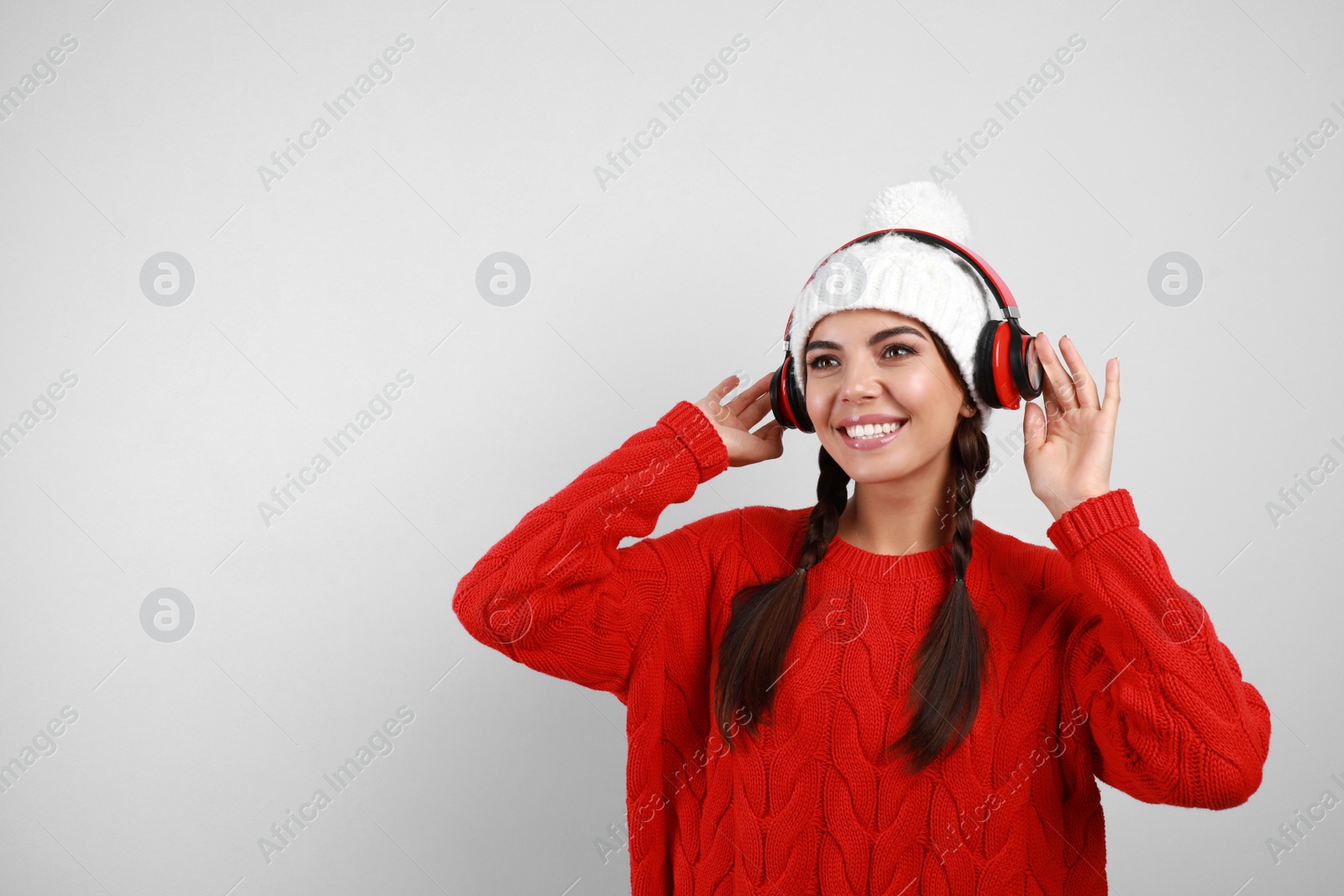 Photo of Young woman listening to music with headphones on grey background, space for text