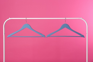 Photo of Metal rack with clothes hangers on color background