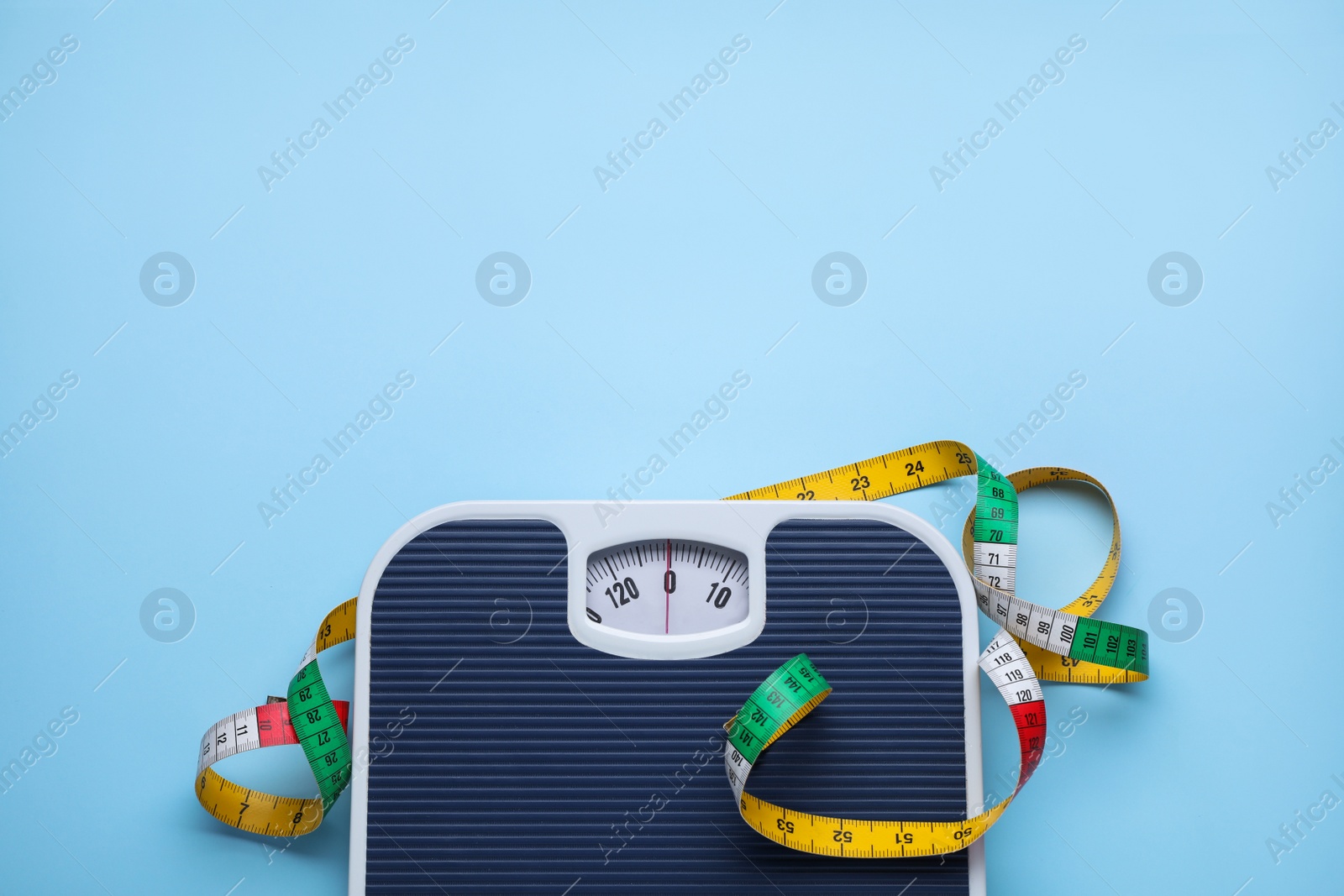 Photo of Scales and measuring tape on light blue background, flat lay. Space for text