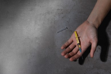 Drug addiction. Man with syringe on grey table, top view and space for text