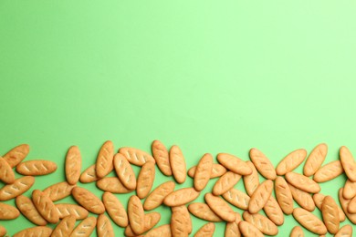 Photo of Delicious crackers on light green background, flat lay. Space for text