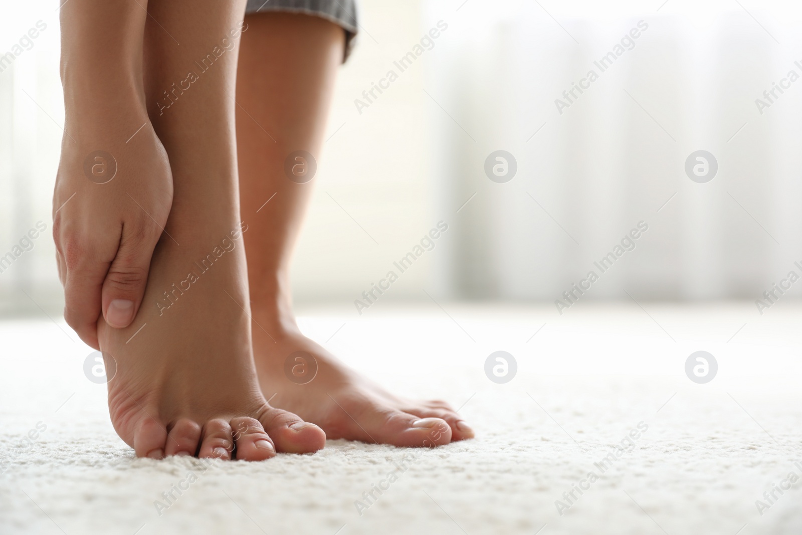 Photo of Young woman suffering from pain in foot indoors, closeup