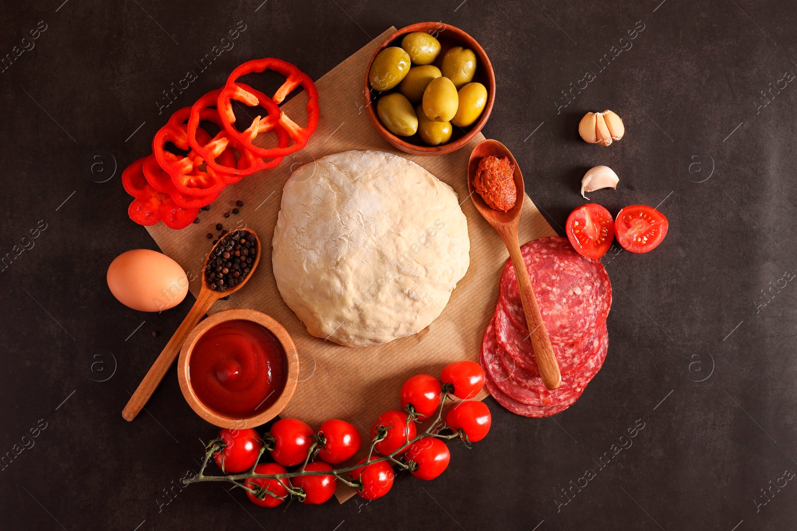 Photo of Pizza dough and products on dark table, flat lay