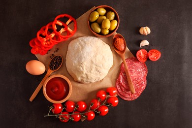 Photo of Pizza dough and products on dark table, flat lay