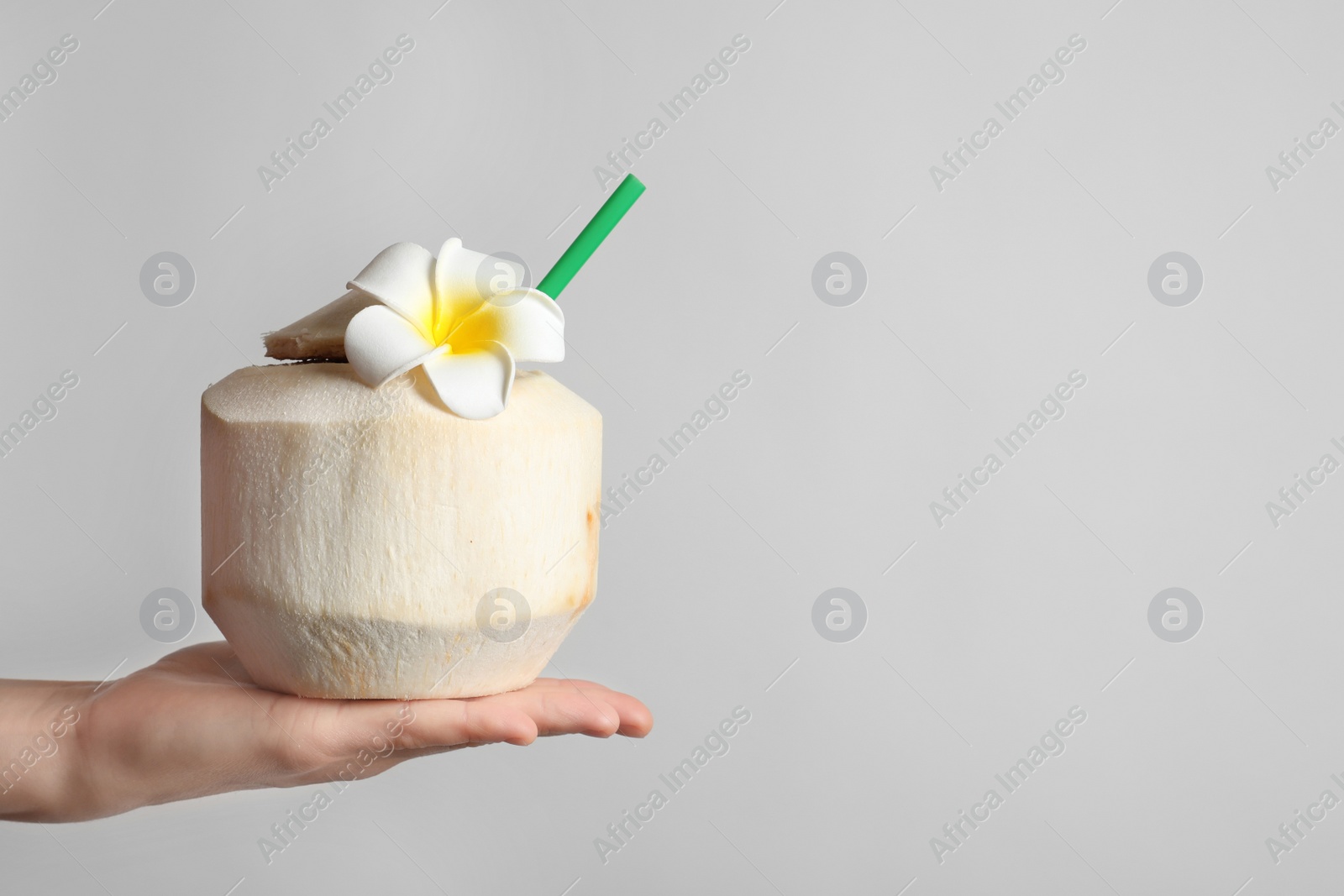 Photo of Woman with fresh coconut drink in nut on light background, closeup