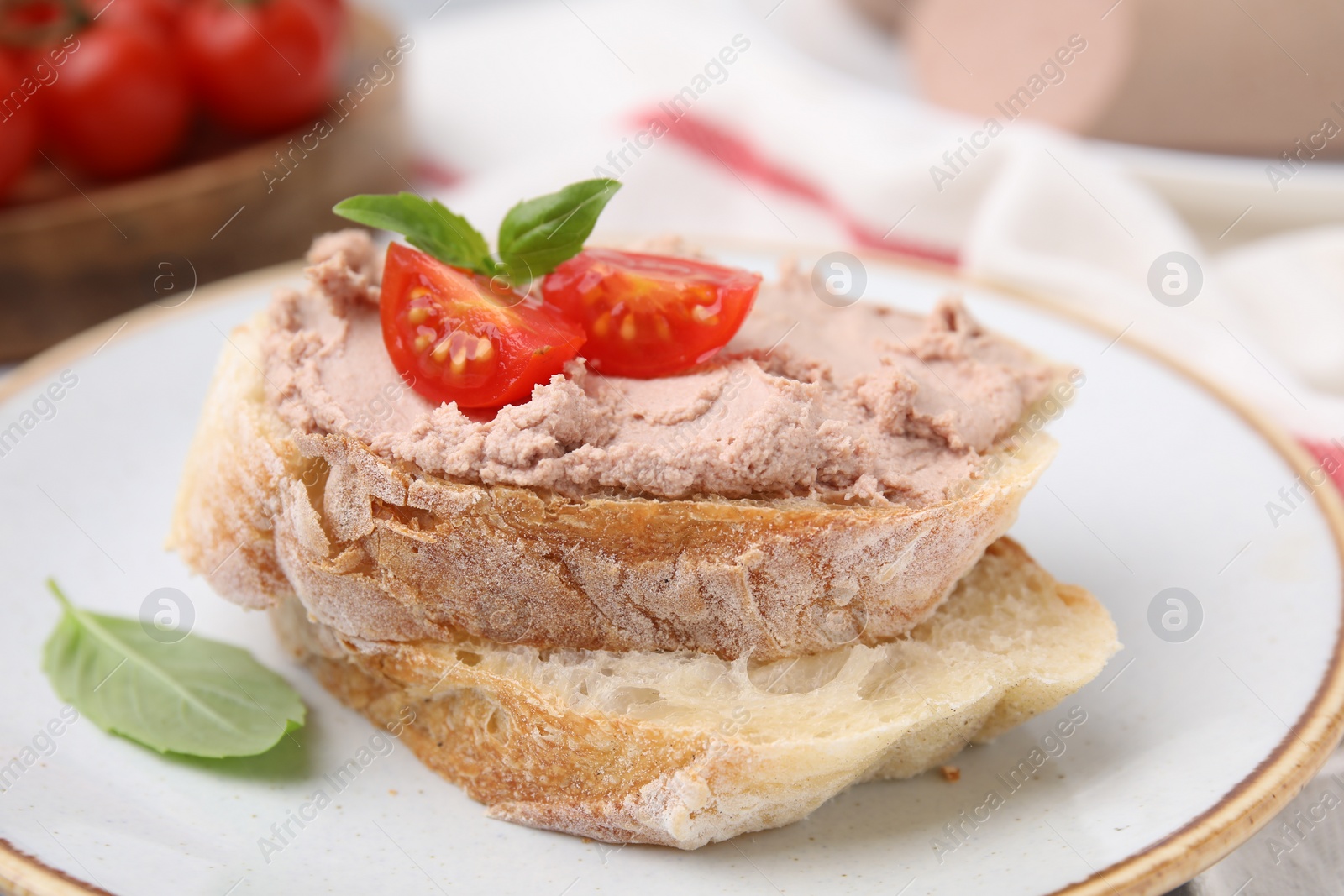 Photo of Delicious liverwurst sandwich with tomatoes and basil on table, closeup