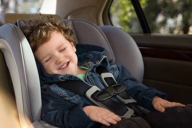 Photo of Cute little boy sitting in child safety seat inside car
