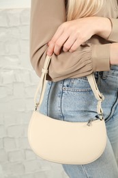 Photo of Woman with stylish baguette handbag near white wall, closeup