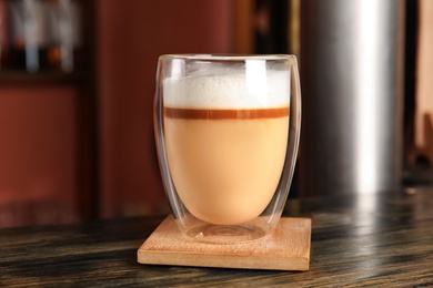 Photo of Glass with delicious latte on wooden table