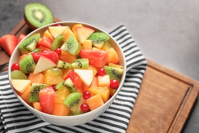 Photo of Bowl with fresh cut fruits on wooden board