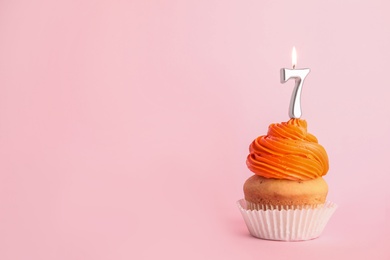 Photo of Birthday cupcake with number seven candle on pink background, space for text