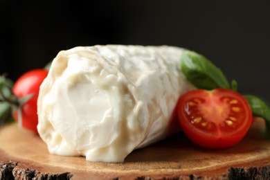 Photo of Delicious fresh goat cheese with tomatoes on wood, closeup