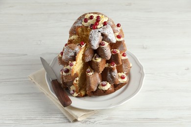 Photo of Delicious Pandoro Christmas tree cake with powdered sugar and berries on white wooden table