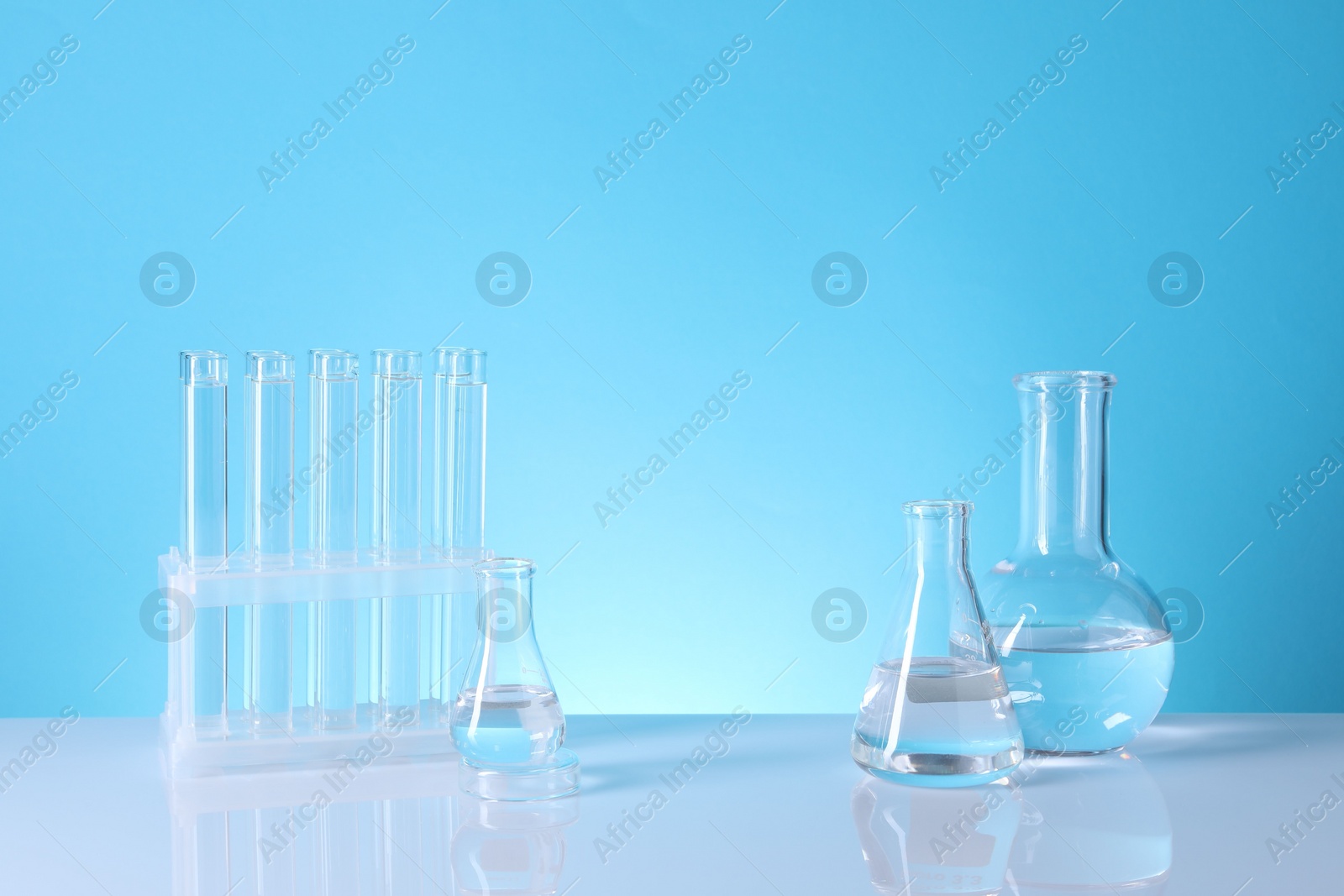 Photo of Laboratory analysis. Glass test tubes and flasks on table against light blue background