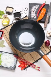 Photo of Wok, chopsticks and different products on white wooden table, above view