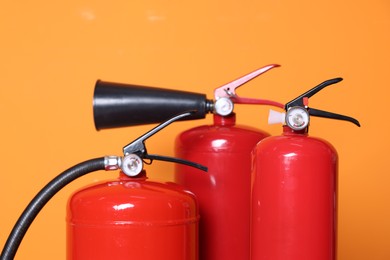 Photo of Three red fire extinguishers on orange background, closeup