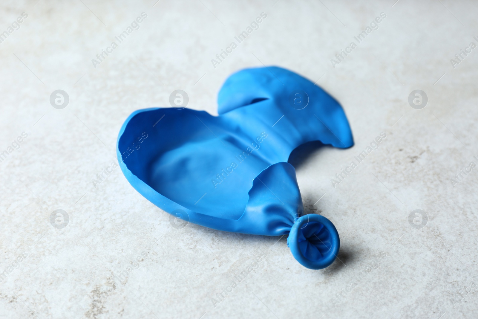 Photo of Popped blue latex balloon on grey background