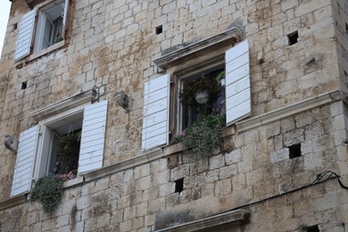 Photo of Beautiful old building with brick wall, potted plants and windows